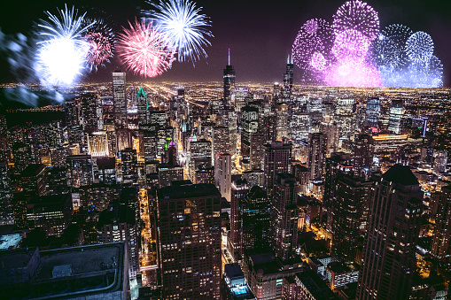 Spectacular fireworks burst brightly in the night sky, illuminating the city skyline below. A testament to celebrations and festivities, the image captures the essence of urban night events.