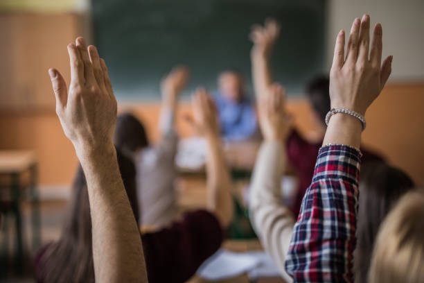 istock Group of unrecognizable students in the classroom with raised arms. 859616020