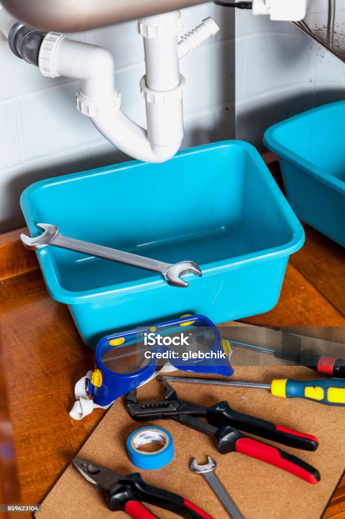 set of tools for repair of  hydraulic valve Before the repair of sanitary siphon. A set of keys, screwdrivers, insulation roll, goggles and pliers laid next Appliance Stock Photo