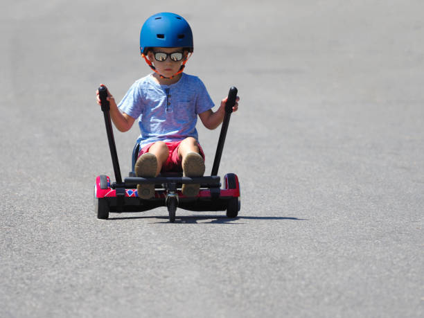 istock Happy boy standing on hoverboard or gyroscooter with kart accessory kit outdoor. New modern technologies 859623992
