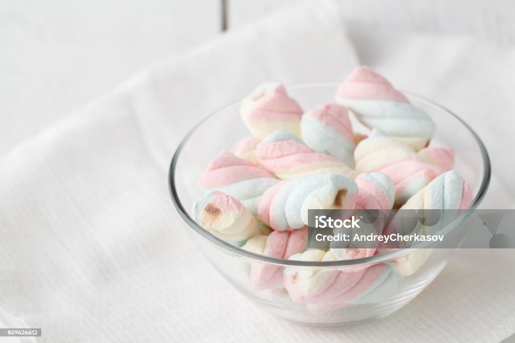 Twisted marshmallows in a cup, over wood background. Bowl Stock Photo