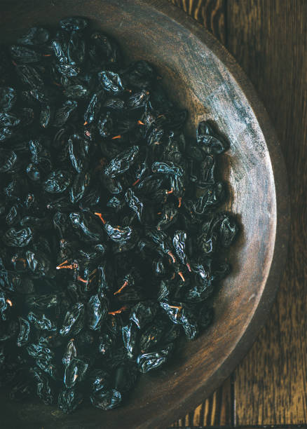 istock Black dried raisins in vintage plate over rustic wooden background 859626764