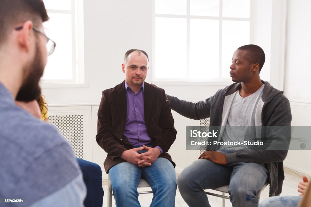 Meeting of support group, therapy session Meeting of support group. Depressed man sitting at rehab group therapy. Psychotherapy, depression, life issues concept Psychotherapy Stock Photo