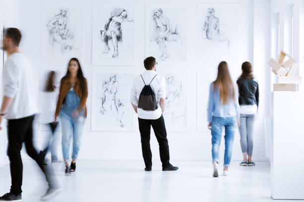 Man with rucksack in gallery Young man with rucksack on back visiting art gallery with drawings and sculpture audience photos stock pictures, royalty-free photos & images