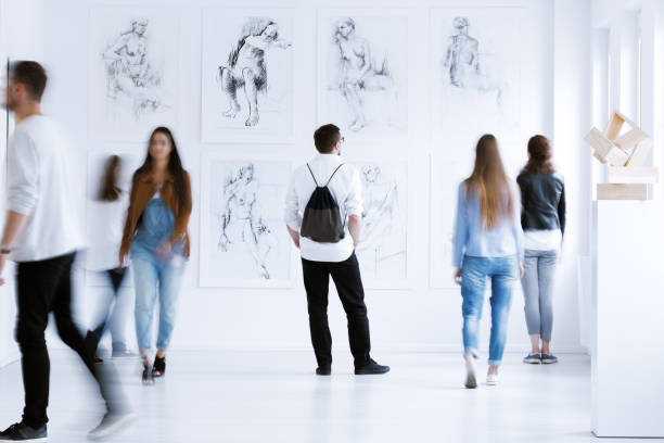 Man with rucksack in gallery Young man with rucksack on back visiting art gallery with drawings and sculpture gallery opening stock pictures, royalty-free photos & images