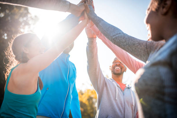 This is gonna be great day! Group of friends exercising outdoors in a park on a sunny day. They put hands together. military camp stock pictures, royalty-free photos & images