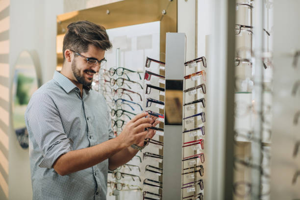 istock Smiling man choosing eyeglasses for himself at optician store. 859646548