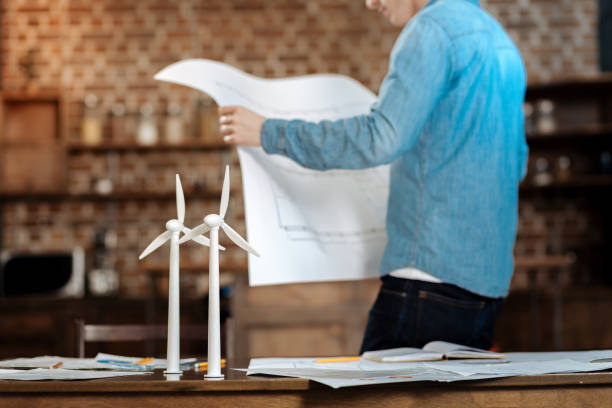 istock Young man scrutinizing blueprint of wind turbines 859654150