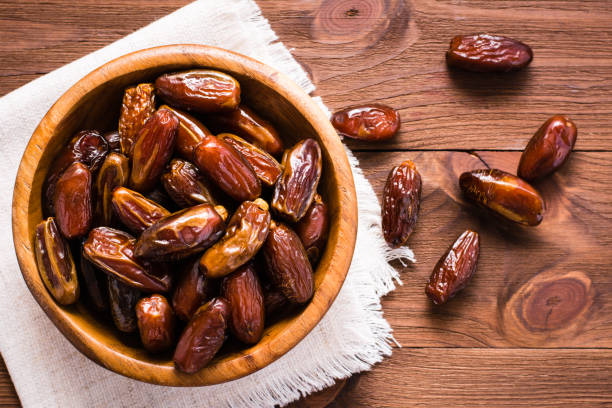 istock Sweet dried dates fruit in a wooden bowl and on the table 859654604