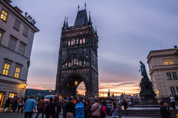 Prague, Czech Republic- People are visiting Charles bridge and passing through old town bridge tower in Prague, Czech Republic at sunset