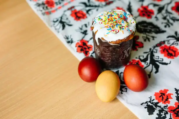 Traditional easter cake kulich Ukrainian style with colored eggs on painted with black and red flowers towel