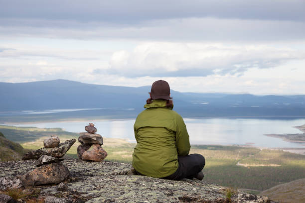 un excursionista femenino sentada sobre un acantilado y mirando el paisaje. - norrland fotografías e imágenes de stock