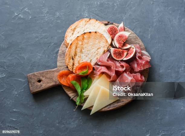 Delicious Appetizers For Wine Or A Snack Prosciutto Figs Bread Cheese On A Rustic Wooden Cutting Board On A Gray Background Top View Stock Photo - Download Image Now