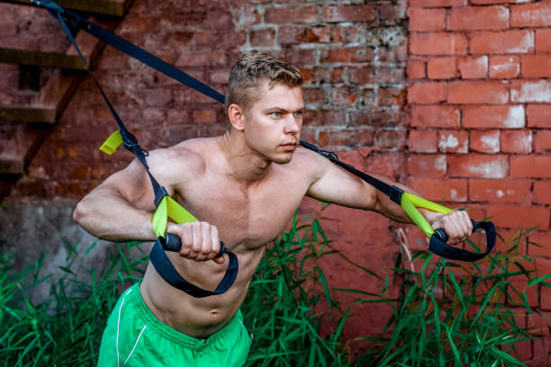 istock Male athlete excellent training training loops, fresh nature in summer, your strength, motivation, close-up. Exercise of muscle is the chest push-up. In evening at wall. Stamina of a man. Against background of stairs. 859665144