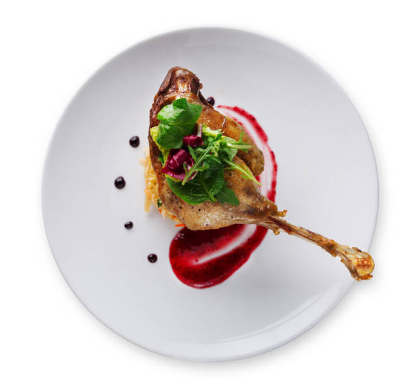Duck confit with berry sauce isolated on white Exclusive restaurant meals. Duck confit with braised cabbage, baked apple and cranberry sauce, isolated on white background, top view confit stock pictures, royalty-free photos & images