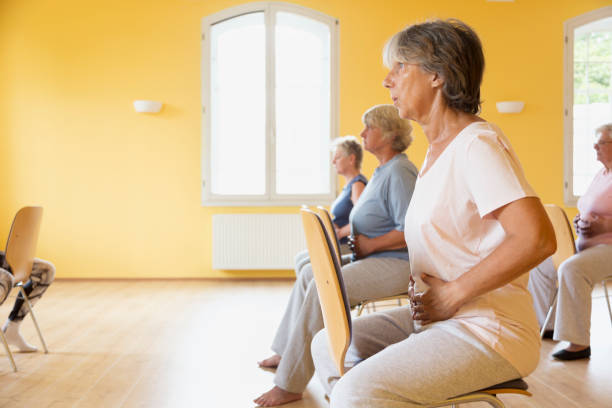 active senior women yoga class on chairs, doing breathing exercise Closeup of active senior women yoga class on chairs, doing breathing exercise, hands on abdomen to feel the movement of breath community health center stock pictures, royalty-free photos & images