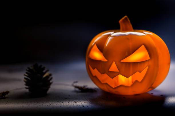istock Halloween pumpkin head jack lantern on dark floor and background with silhouettes pinecone and dry leave on the floor.Halloween party concept. 859676328