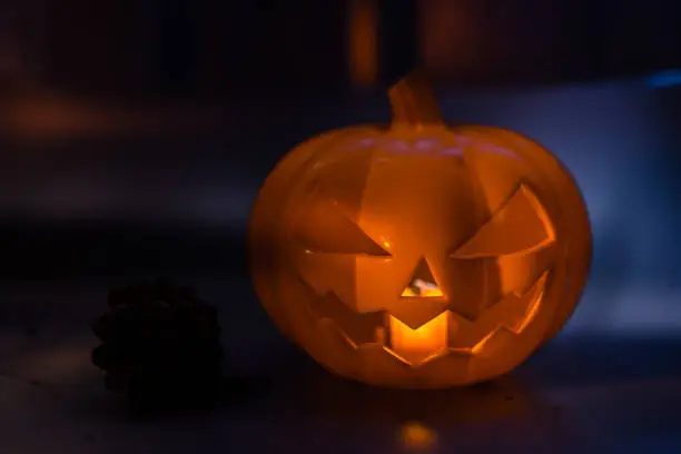 Photo of Halloween pumpkin head jack lantern on dark floor and background. Halloween party concept.