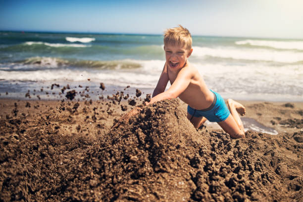 istock Naughty boy destroying someone's sandcastle on the beach 859685522