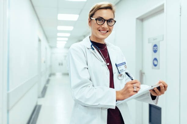 istock Smiling doctor standing in hospital corridor with clipboard 859687662