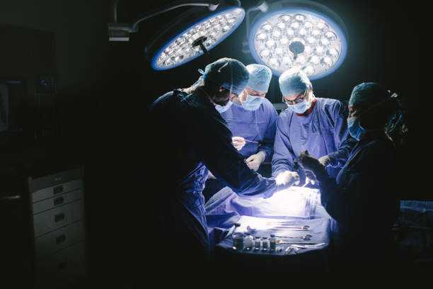 cirujanos realizar procedimiento quirúrgico en quirófano - performance surgery doctor men fotografías e imágenes de stock