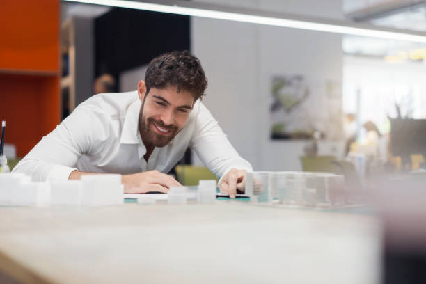 istock Smiling businessman looking at model in office 859691870