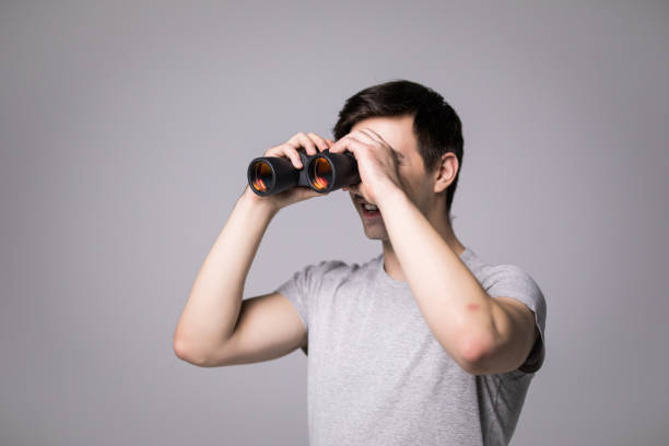 istock Young handsome man with binoculars isolated on white background 859730370