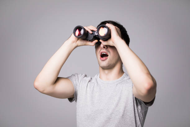 istock Young handsome man with binoculars isolated on white background 859732286