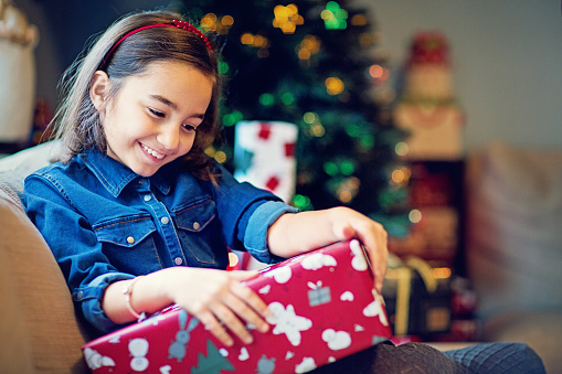 Happy girl is opening her Christmas gift