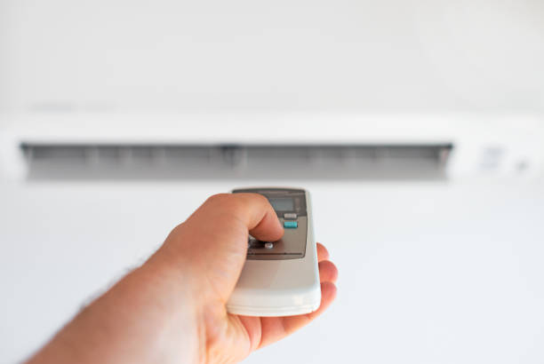 istock Hand holding remote control aimed at the air conditioner. 859734992