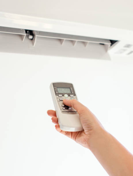istock Hand holding remote control aimed at the air conditioner. 859735224