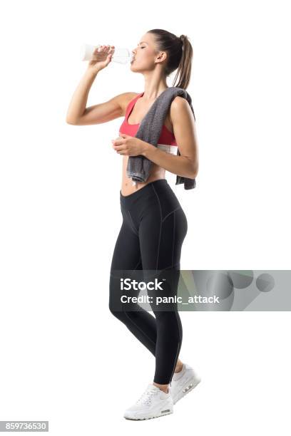Tired Thirsty Female Runner Drinking Water From Glass Bottle With Head Titled Back Stock Photo - Download Image Now
