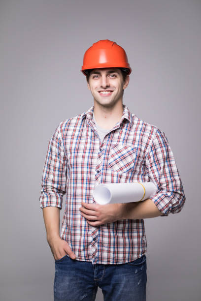 istock Handsome young architect in suit and protective helmet, looking at camera and smiling, on gray background 859739850