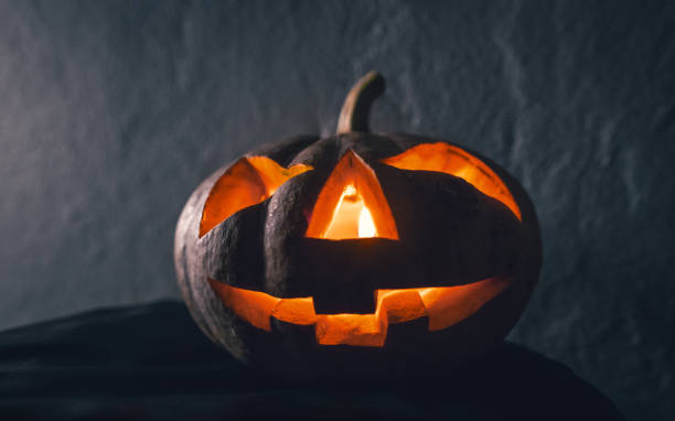 istock halloween pumpkin head with candle light in darkness background 859743196