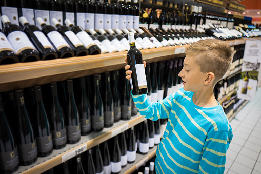 young boy in vine store buying a bottle of vine