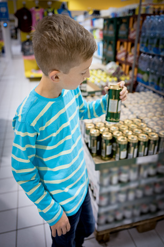 young boy in a store buying a can of beer