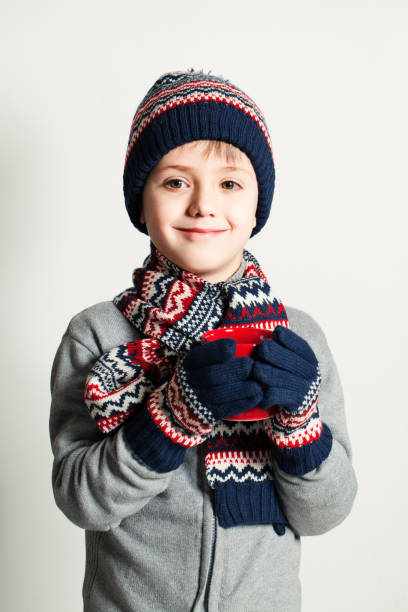 winter child boy drink tea or coffee. winter clothes. sweater, hat and scarf - glove winter wool touching imagens e fotografias de stock