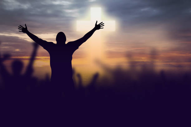 Silhouette of Christian prayers raising hand while praying to the Jesus stock photo