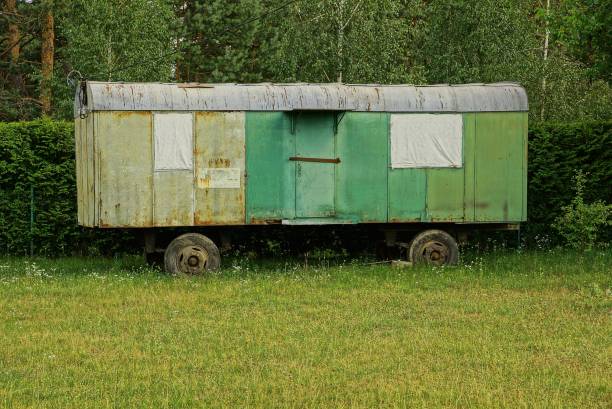old iron container on wheels on green grass behind a fence