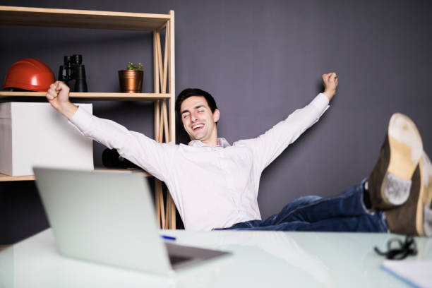 istock Satisfied with work done. Happy young man working on laptop while sitting at his working place in office 859756856