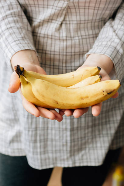 istock Woman holding three ripe bananas in arms 859757066