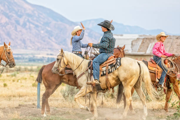 Cowgirl and cowboy congratulate each other while on horseback Cowgirl and cowboy congratulate each other while on horseback texas cowboy stock pictures, royalty-free photos & images