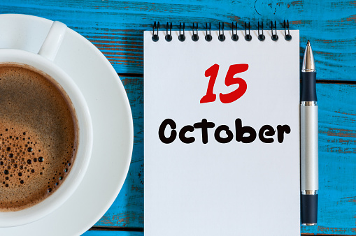October 15th. Day 15 of month, hot coffee cup with calendar on accauntant workplace background. Autumn time. Empty space for text.