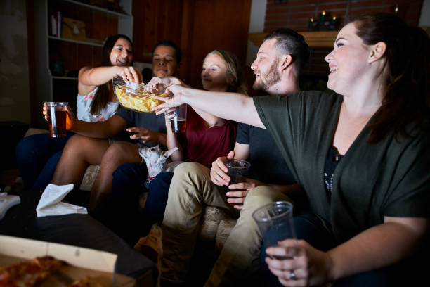 istock friends watching tv at night passing around snacks 859778970