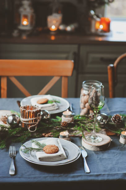 istock Festive Christmas and New Year table setting in scandinavian style with rustic handmade details in natural and white tones. Dining place decorated with pine cones, branches and candles 859779344