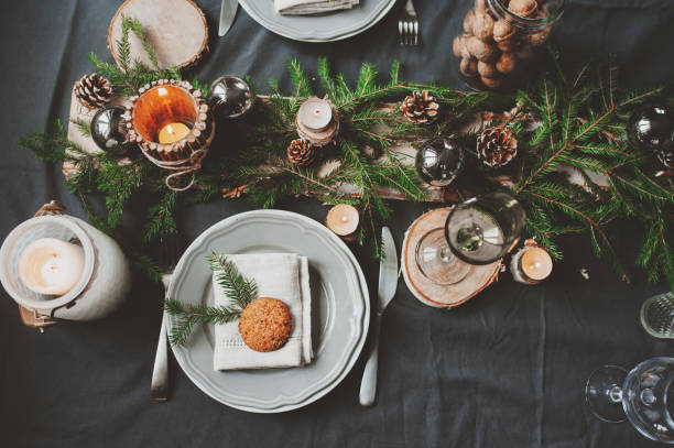 istock Festive Christmas and New Year table setting in scandinavian style with rustic handmade details in natural and white tones. Dining place decorated with pine cones, branches and candles 859779374