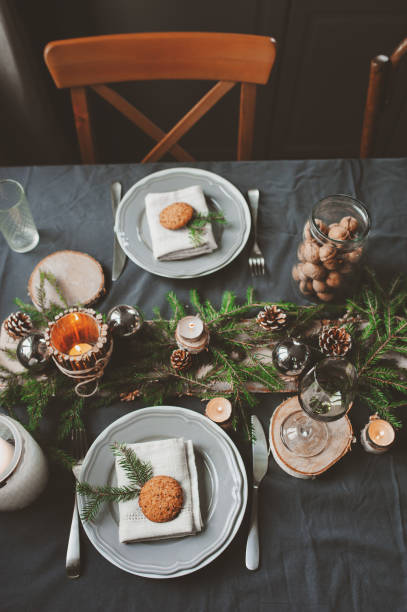 istock Festive Christmas and New Year table setting in scandinavian style with rustic handmade details in natural and white tones. Dining place decorated with pine cones, branches and candles 859779376