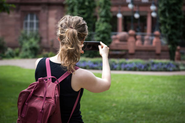 una mujer está tomando una fotografía con su teléfono móvil - mobilestock outdoors horizontal rear view fotografías e imágenes de stock