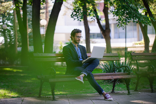 Handsome young bearded businessman, enjoying his leisure time in the park.