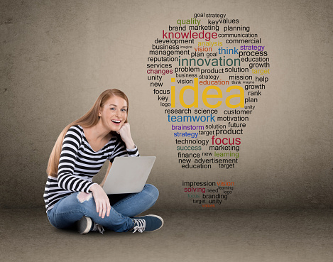Young woman success using laptop in front of light bulb shaped word cloud